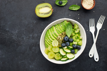 Green vegetables fruit detox balance salad bowl. Avocados, cucumbers, cherry tomatoes, blueberries, celery, grapes. Juicy cream crispy dish without meat