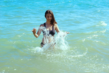 brunette girl bathes in the sea, splashing water