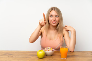 Young blonde woman having breakfast touching on transparent screen