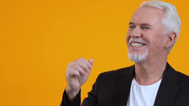 Happy aged gentleman showing air kiss gesture on bright background, admiration