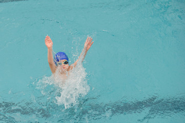 top view of a 7-year boy playing and swimming in the swimming pool