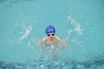 top view of a 7-year boy playing and swimming in the swimming pool