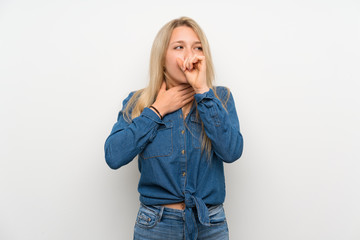 Young blonde woman over isolated white wall is suffering with cough and feeling bad