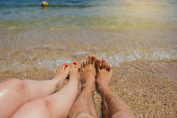 top view of man and woman legs on the beach