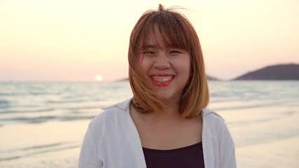 Young Asian woman feeling happy on beach, beautiful female happy relax smiling fun on beach near sea when sunset in evening. Lifestyle women travel on beach concept.
