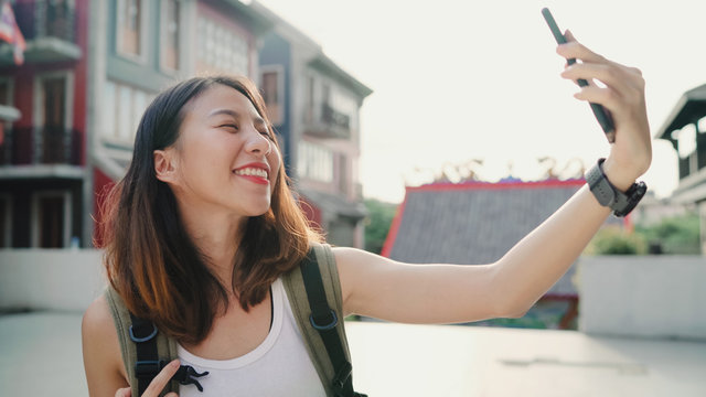 Cheerful beautiful young Asian backpacker blogger woman using smartphone taking selfie while traveling at Chinatown in Beijing, China. Lifestyle backpack tourist travel holiday concept.