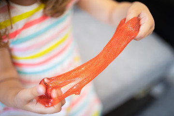 Little girl holding red slime with glitter