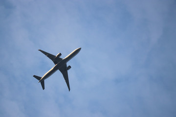 Airplane flying in the blue sky, air travel. Silhouette of commercial twin-engine plane taking off on background of white clouds, turbulence concept