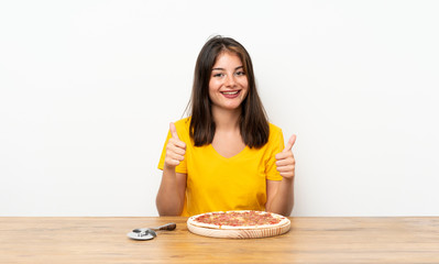 Caucasian girl with a pizza giving a thumbs up gesture