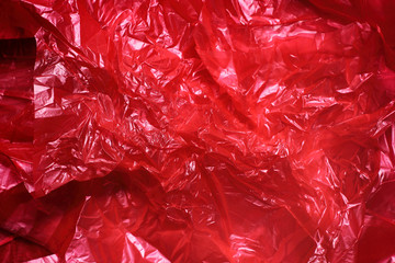Red clear plastic bag texture background. Waste recycling concept. Crumpled polyethylene and cellophane.