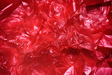 Red clear plastic bag texture background. Waste recycling concept. Crumpled polyethylene and cellophane.