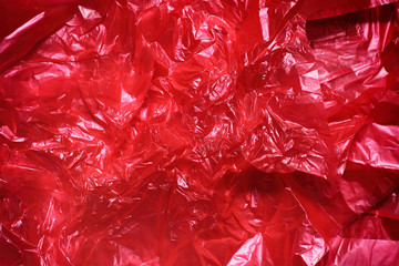 Red clear plastic bag texture background. Waste recycling concept. Crumpled polyethylene and...