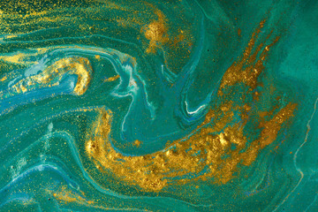 Liquid uneven blue and green marbling pattern with golden glitter and glare of light
