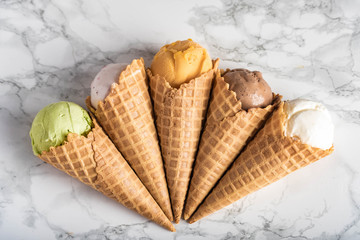 assorted ice creams in waffle cone on marble background