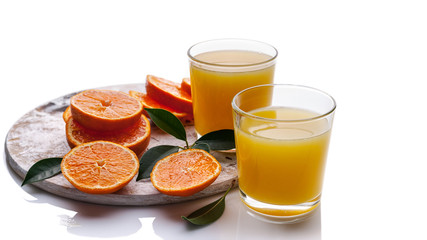 Glasses with orange juice and orange slices on a white background.