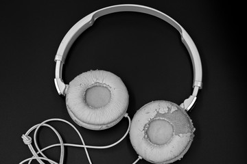 Old white headphones on black background