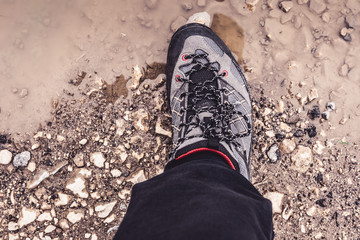Male Leg Wearing Sportive Hiking Sneakers Shoes in Mud and Water. Trekking Footwear for Mountain Walking Trail.