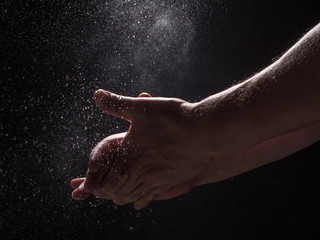 Fototapeta na wymiar A Caucasian Man's Hands Clapping Together in an Explosion of Water - with a Black Background