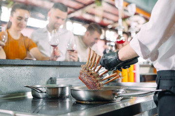 The chef prepares food in front of the visitors in the restaurant