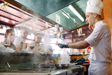 The chef prepares food in front of the visitors in the restaurant