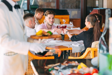 Obraz na płótnie Canvas Friends drink wine on the terrace of the restaurant.