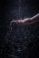 A Stream of Water Pouring Down a Caucasian Man's Hands - Splashing Droplets of Water Everywhere with a Black Background