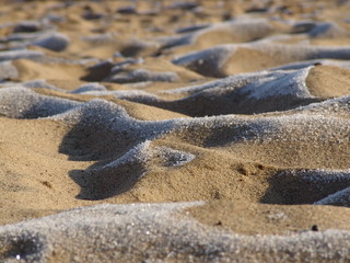 Sand in the hoarfrost on the river bank. Snow on the sand dunes early in the morning.