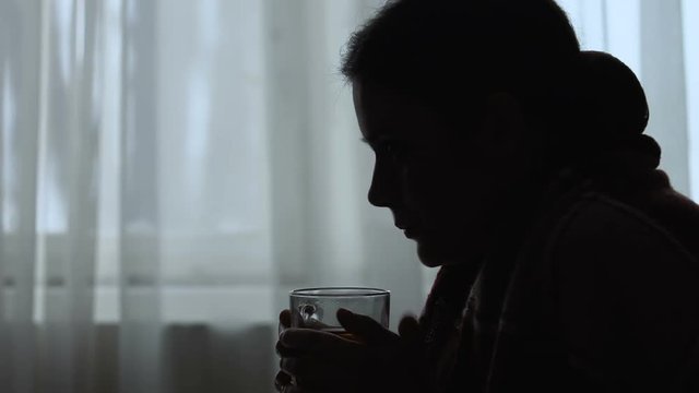 Silhouette of shivering woman suffering fever, drinking hot tea, flu treatment