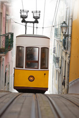 Yellow tram on narrow street on a steep hill in the beautiful city of Lisboa