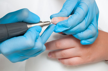 Woman use electric nail file drill in beauty salon. Perfect nails manicure process or operation in close up.