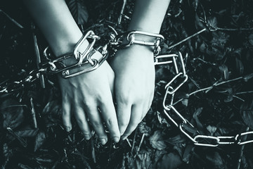 Women's hands chained in a dark forest - the concept of violence, hostage, slavery