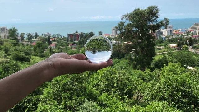 hand holding magic crystall ball over beautiful nature landscape, travel concept