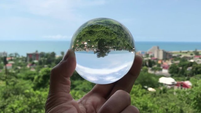 hand holding magic crystall ball over beautiful nature landscape, travel concept