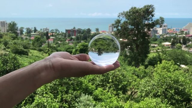 hand holding magic crystall ball over beautiful nature landscape, travel concept