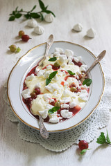 Eton mess, traditional English dessert with gooseberry, whipped cream and meringue on a light background. Rustic style.