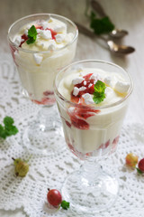 Eton mess, traditional English dessert with gooseberry, whipped cream and meringue on a light background. Rustic style.