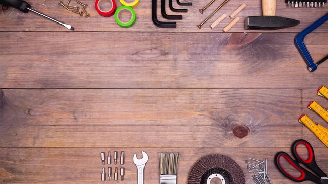 Different DIY tools appears and disappears on wooden background with copyspace in center. Top view. Stop motion animation. 4k.