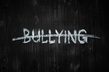 Bullying word crossed out on black wood background. Sign, concept of dealing with behaviour social...