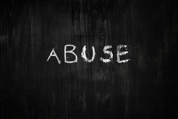 Abuse word handwritten on black wood background. Sign, concept of dealing with behaviour social issues - the word 