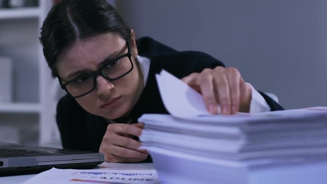 Unmotivated stressed office worker looking through papers, work overload closeup