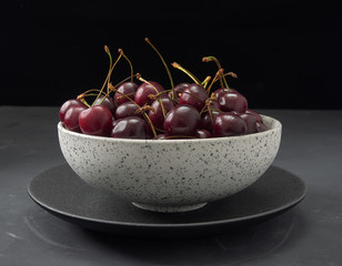 Delicious juicy cherries,lying on a beautiful plate.On wood background