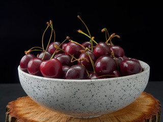 Delicious juicy cherries,lying on a beautiful plate.On wood background