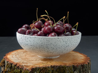 Delicious juicy cherries,lying on a beautiful plate.On wood background