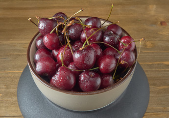 Delicious juicy cherries,lying on a beautiful plate.On wood background