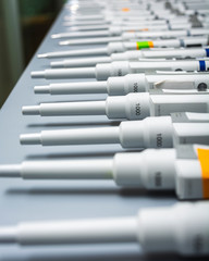 row of pipettes turned on their sides on a grey table top after being cleaned.