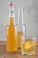 The glass of Kombucha drink with lemon and two bottles.