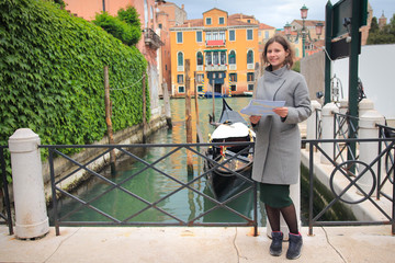 Girl tourist with city map in Venice, Italy. Happy vacation in Venezia. Woman on water canal and gondola background