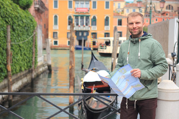 Fototapeta na wymiar Man with city map in Venice, Italy. Guy travel in Venezia. Man near gondola in water street canal