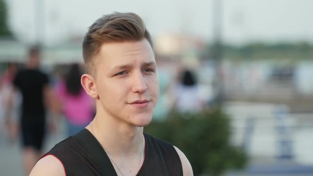 not satisfied young stylish man with blond hair tasting (smoking) electronic system of heating tobacco on the street, Close up