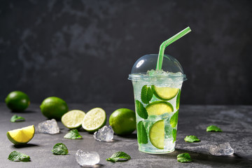 Cold refreshing   mojito in a plastic clear cup on a  black background. With space for your text.